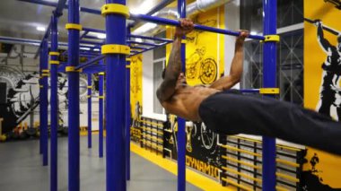 Genç Afrikalı sporcu spor kulübündeki yatay barda jimnastik numaraları gösteriyor. Spor salonunda statik egzersizler yapan kaslı Afro-Amerikan sporcu. Sportif yaşam tarzı kavramı.