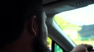Araba kullanan erkek sürücünün profili. Araba kullanırken yola dikkat eden ciddi bir adamın yüzünü kapatın. Yolculuk sırasında arabasının direksiyonunu tutan sakallı adam. Aile gezisi kavramı.