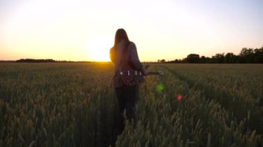 Uzun saçlı hippi adam elinde elektro gitarla yeşil arpa çayırında yürüyor. Müzik aleti olan genç bir hippi buğday tarlasına gidiyor ve gün batımında sigara içiyor..