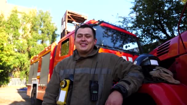Πορτρέτο Του Χαρούμενου Νεαρού Πυροσβέστη Στολή Στο Φόντο Ενός Πυροσβεστικού — Αρχείο Βίντεο