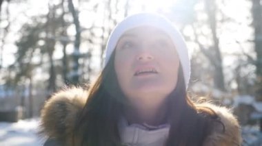 Çekici bir kadının portresi yürümekte ve güzel kış manzaralarına hayran olmaktadır. Çekici kız kış ormanlarında dolaşıp etrafa bakınıyor. Güneşli kış gününde gezen bir bayan. Yavaş çekim. Yakın çekim..