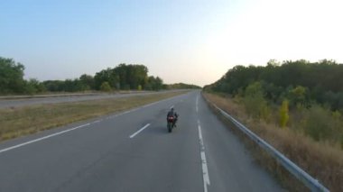 Otobanda motosiklet süren motosikletli bir motorcunun kamera görüntüsü. Motosikletli gün batımında kır yolunda motosikletiyle yarışıyor. Yolculuk sırasında bisiklete binen adam. Özgürlük ve macera kavramı.