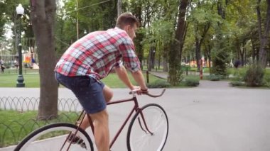Vintage binmek açık genç yakışıklı adamı takip et. Sportif adam parkta Bisiklete binme. Sağlıklı aktif yaşam tarzı. Yan görünümü kapatmak yavaş hareket.