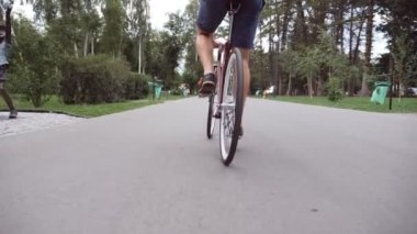 Park yolunda antika bir bisiklet süren genç bir adam. Sportif adam dışarıda bisiklet sürüyor. Sağlıklı aktif yaşam tarzı. Düşük açı. Ağır çekim..