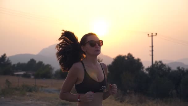 Sportliches Mädchen Joggt Bei Sonnenuntergang Auf Einer Landstraße Junge Frau — Stockvideo
