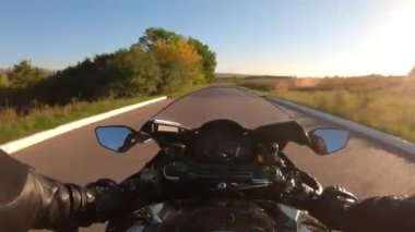 Kırsal yolda motosiklet süren birinin bakış açısı. Motosikletlinin boş bir güzergahta motosiklet sürmesinin bakış açısı. Yaz seyahati boyunca motosikletiyle yarışan bir adam. POV.