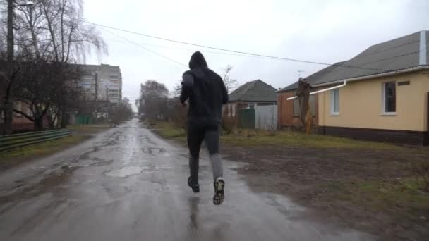 雨の中 田舎道を走る強いアスリートたち 若いスポーツマンは 曇った日の田舎のトレイルでジョギングします 屋外で運動するスポーティな男性 健康的なアクティブライフスタイルの概念 クローズアップ — ストック動画