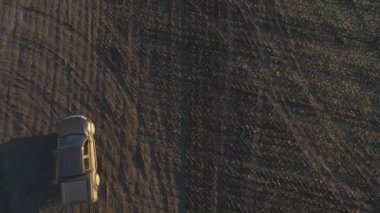 Sonbaharda tarlaların arasında uçan bir araba. Hasattan sonra tarladan geçen bir kamyonet. Otlakta giden off-road aracı. Tarım çiftçiliği kavramı. Hava görüntüsü.