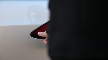 Male hand is plugging in power cord to an electric car. Arm inserts power connector into EV car. Person charging electrical auto at charging station. Environment friendly with zero emission. Close up.