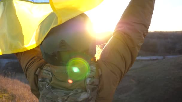 女兵身穿制服 头戴乌克兰国旗的头盔 在山岗上躲避日落 军医举着国家的黄色蓝色旗帜 战胜侵略的胜利抵抗入侵的概念 — 图库视频影像