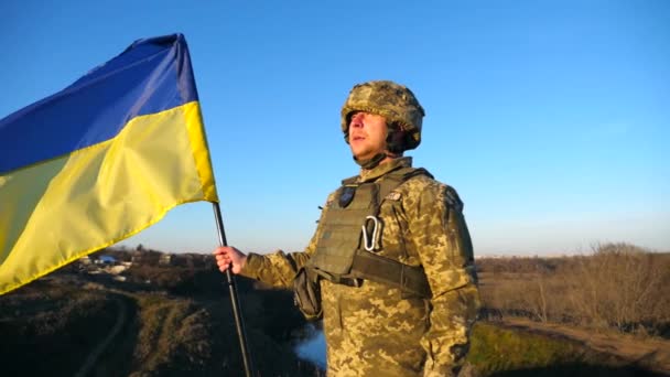 身穿军服的军人站在山顶上 高举乌克兰国旗 举着乌克兰国旗的男兵 战胜俄国侵略的胜利抗入侵的概念 慢动作 — 图库视频影像