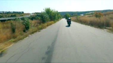 Kırsal kesimde motosiklet kullanan motosikletliyi takip edin. Golf yolunda motosiklet yarışı motosikleti. Yolculuk sırasında bisiklet süren adam. Yolculukta özgürlük ve macera kavramı. Hava görüntüsü.