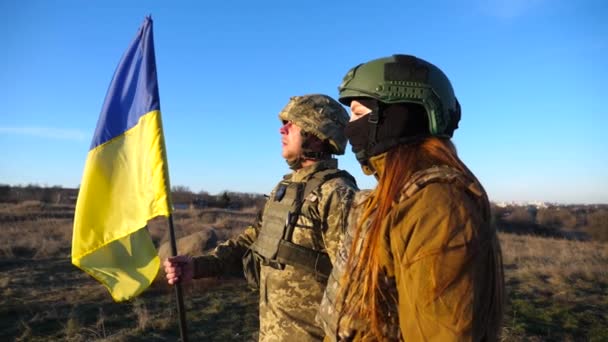 ウクライナの旗を掲げているウクライナ軍の兵士 制服を着た軍人は青空に向かって旗を掲げた ロシア侵略に対する勝利 侵入抵抗コンセプト スローモーション — ストック動画