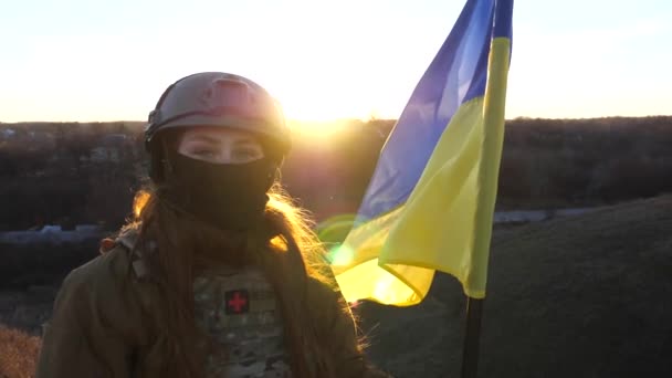 軍服の女性は日没に反対し ウクライナの国旗を掲げた ウクライナ軍の女性兵士が旗を掲げている 侵略に対する勝利 侵入抵抗コンセプト スローモーション — ストック動画