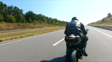 Bisikletçi yaz günü yol gezisi sırasında motosiklet sürüyor. Adam otoyolda modern spor motosikletle hızlı gidiyor. Motosikletli, kır yolunda bisikletiyle yarışıyor. Macera kavramı. Hava görüntüsü.
