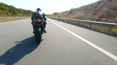 Bisikletçi yaz günü yol gezisi sırasında motosiklet sürüyor. Adam otoyolda modern spor motosikletle hızlı gidiyor. Motosikletli, kır yolunda bisikletiyle yarışıyor. Macera kavramı. Hava görüntüsü.