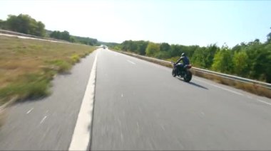 Bisikletçi yaz günü yol gezisi sırasında motosiklet sürüyor. Adam otoyolda modern spor motosikletle hızlı gidiyor. Motosikletli, kır yolunda motosikletiyle yarışıyor. Macera kavramı. Hava görüntüsü.