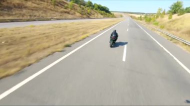 Yaz günü otoyolda hızlı giden bir adamın havadan çekilmiş fotoğrafı. Motosikletli, kır yolunda motosikletiyle yarışıyor. Yolculuk sırasında bisiklet süren bir adam. Özgürlük ve macera kavramı.