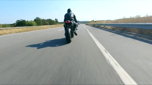 高速道路で現代のスポーツバイクに乗るオートバイに従ってください バイカーは田舎道でバイクを走らせている 旅行中にバイクを運転する男 旅の自由と冒険の概念 空中射撃 — ストック動画