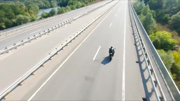バイカーは夏の旅行中にバイクを運転しています 高速道路で近代的なスポーツバイクに乗る男 バイクで自転車を走るバイクを国道で走る 冒険の概念について アリアルショット — ストック動画