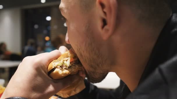 Jovem Com Barba Come Hambúrguer Cheeseburger Restaurante Fast Food Boca — Vídeo de Stock