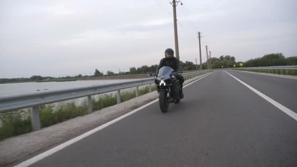 オートバイは国道でバイクをレースする ヘルメットに乗っている若者は 田舎のルートで近代的なスポーツバイクに乗ります 旅行中に自転車を運転する男 旅行と自由という概念 スローモーション — ストック動画