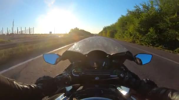 ハイウェイでバイクを運転するバイクを太陽フレアで観察するポイント オートバイライダーの視点は 日没時にスピードロードに乗ります 夏の旅でバイクをレースする男 パブリック — ストック動画