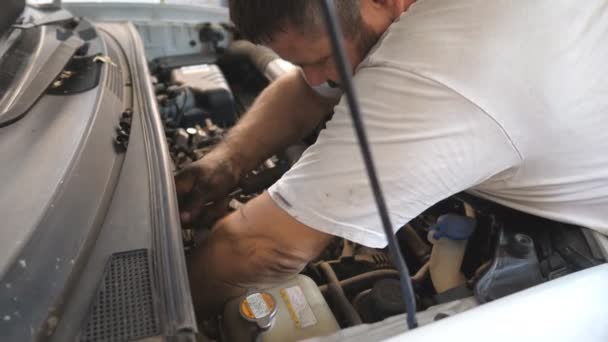 수선공은 워크숍에서 엔진을 장착하고 자동차 정비공 주차장에서 밑에서 일하고 있습니다 — 비디오