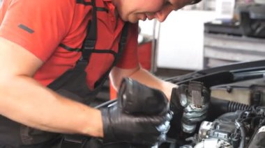 Profesyonel oto tamircisi araç kaputu altında çalışır. Tamirci atölyede ya da serviste bir arabanın motorunu tamir ediyor. Garajda otomobil motoru kontrol eden bir adam var. Bakım ve tanı konsepti. Yakın çekim.