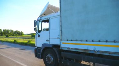 Kargo karavanıyla otoyolda giderken ve gün batımında mal taşırken yan görüş. Kamyon kırsal yoldan geçerek hedefe gidiyor. Kargo taşıma konsepti. Yavaş çekim. Yakın çekim..