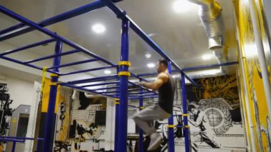 Genç kaslı atlet modern spor salonundaki yatay barda performansını sergiliyor. Jimnastik yapan güçlü sporcu fitness merkezinde spor ekipmanları üzerinde çalışıyor. Sportif yaşam tarzı kavramı. Yavaş çekim