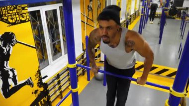 Modern spor salonundaki yatay barda egzersiz yapan güçlü bir Afrikalı atlet. Kaslı Afro-Amerikan sporcusu içeride çalışıyor. Genç siyahi adam fitness kulübünde antrenman yapıyor. Sportif aktif yaşam tarzı.