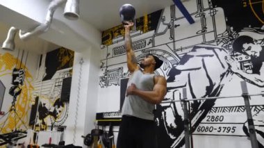 Spor kulübünde ağır kettlebell kaldıran güçlü bir Afrikalı. Kaslı Afro-Amerikan sporcusu modern spor salonunda sıkı ve yoğun idman yapıyor. Sağlıklı ve aktif yaşam tarzı kavramı. Yavaş çekim.