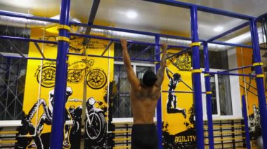 Güçlü bir Afro-Amerikan atleti modern spor salonunda barfiks çekiyor. Spor kulübünde spor yapan kaslı siyah bir sporcu. Genç Afrikalı adam spor salonunda eğitim görüyor. Sağlıklı aktif yaşam biçimi.