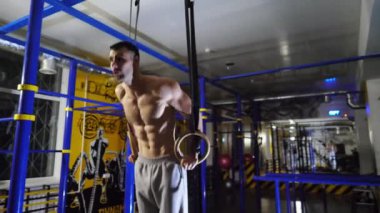 Spor kulübünde şınav çeken güçlü bir sporcu. Kaslı üstsüz sporcu içeride sıkı çalışıyor. Modern spor salonunda genç erkek jimnastikçi eğitimi. Sağlıklı ve aktif yaşam tarzı kavramı.