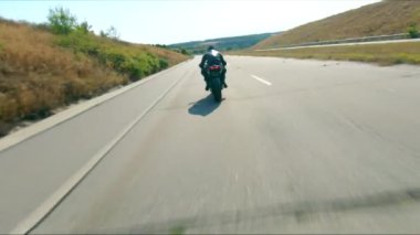 Yazın otobanda, modern spor motosikletle hızlı giden bir adamın hava görüntüsü. Motosikletli hız yolunda motosikletiyle yarışıyor. Yolculuk sırasında bisiklet süren adam. Özgürlük ve macera kavramı.