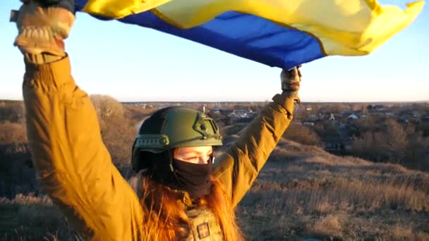 拿着乌克兰国旗的乌克兰女兵 身着军服的女孩在蓝天的映衬下升起了黄蓝色的旗帜 战胜俄国的侵略和战争的结束 靠近点 — 图库视频影像