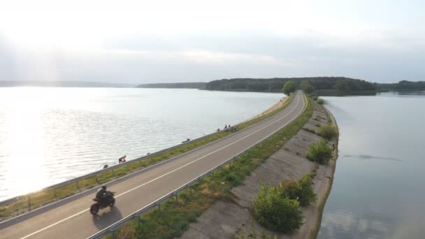 Повітряний Постріл Велосипедиста Їде Мотоциклі Через Дорогу Біля Озера Мотоцикліст — стокове відео