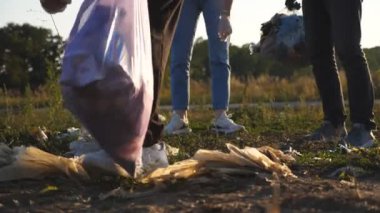 Eldivenli küçük bayan çocuğu yakından çek çöpleri torbaya koy kırsal kesimde doğayı kurtar. Kızın ailesi arka plandaki kağıt atıklarını temizlemeye yardım ediyor. Çevresel sorun kavramı.