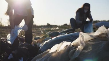 Eldivenli küçük kızı olan genç ebeveynler yol kenarında çöp topluyor. Maskeli çevrecilerin ailesi plastik ve kağıt atıklarını temizliyor. Çevresel sorun kavramı. Dolly vurdu.