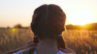Güzel bayan çocuk çim tarlasında duruyor, sarı saçlarını düzeltiyor. Meadow 'da güzel bir akşam gün batımını seyreden tatlı küçük kız. Bulanık arka plan. Özgürlük kavramı. Arka görünüm.