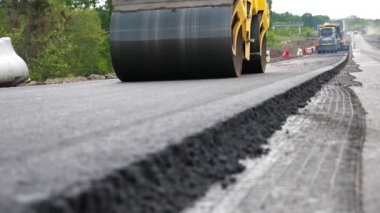 Paten yeni asfalt tabakası seriyor. Yol yapımı özel makineler. Sıkıştırıcı otoyol yapımı. Steamroller yavaşça sürüyor. Ağır makinelerle yol onarımı. Yol çalışması ve otoyol bakımı kavramı