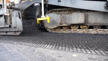 Yeni asfalt tabakasını yavaşça döşeyen bir paten. Kırsal alanda yol yapan özel makineler. Sıkıştırıcı otoyol yapımı. Ağır makineler yolu onarıyor. Yol çalışması süreci. Yol onarımı.