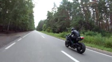 Orman yolundaki motosikletli motorcuları takip edin. Kasklı adam ormanın yakınındaki kırsal yolda modern spor motosiklet yarışı yapıyor. Yolculuk sırasında ya da yolculukta bisiklet süren adam. Özgürlük kavramı.