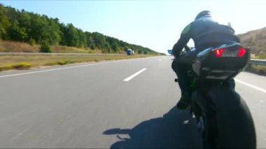 Bisikletçi yaz günü yol gezisi sırasında motosiklet sürüyor. Adam otoyolda modern spor motosikletle hızlı gidiyor. Motosikletli, kır yolunda bisikletiyle yarışıyor. Macera kavramı. Hava görüntüsü.