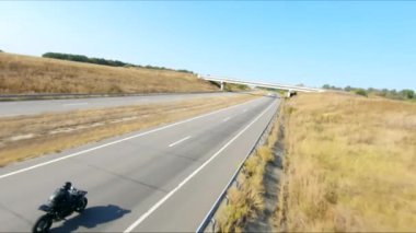 Yaz günü otoyolda hızlı giden bir adamın havadan çekilmiş fotoğrafı. Motosikletli, kır yolunda motosikletiyle yarışıyor. Yolculuk sırasında bisiklet süren bir adam. Özgürlük ve macera kavramı.