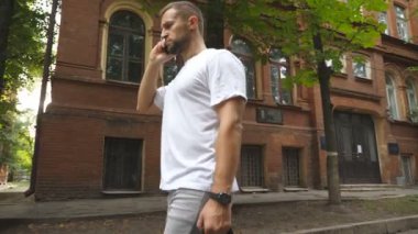 Şehir içinde yürürken telefonla konuşan ciddi bir adam. Gündelik giysiler içindeki genç girişimci cep telefonuyla iş görüşmesi yapıyor. İş ve alet kavramını kullanıyor. Yavaş çekim.