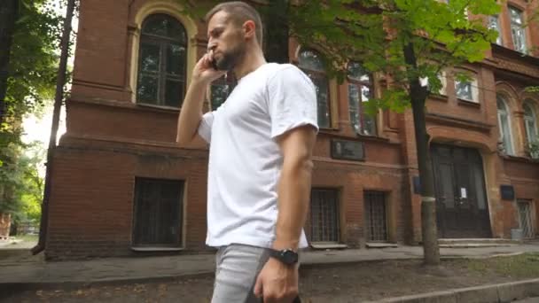 Hombre Serio Hablando Por Teléfono Mientras Camina Por Área Urbana — Vídeos de Stock