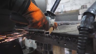 Ustabaşı metal kesmek için testere kesme makinesi kullanıyor. Garajda ya da atölyede çeliği kesen dairesel testereli bir adam. Metal öğüten endüstriyel işçiler. Sıcak metalden kıvılcımlar çıkıyor. Yavaş çekim.