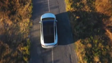 Şehir yolunda uçan elektrikli arabanın görüntüsü. Yeni akıllı araç otoyolda hızla ilerliyor. Çevre temiz otomobil otoyol boyunca elektrik yüküne biniyor. Kırsal alanda trafik vardı. Üst görünüm.